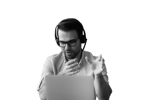 A man talking on a headset, on a laptop.